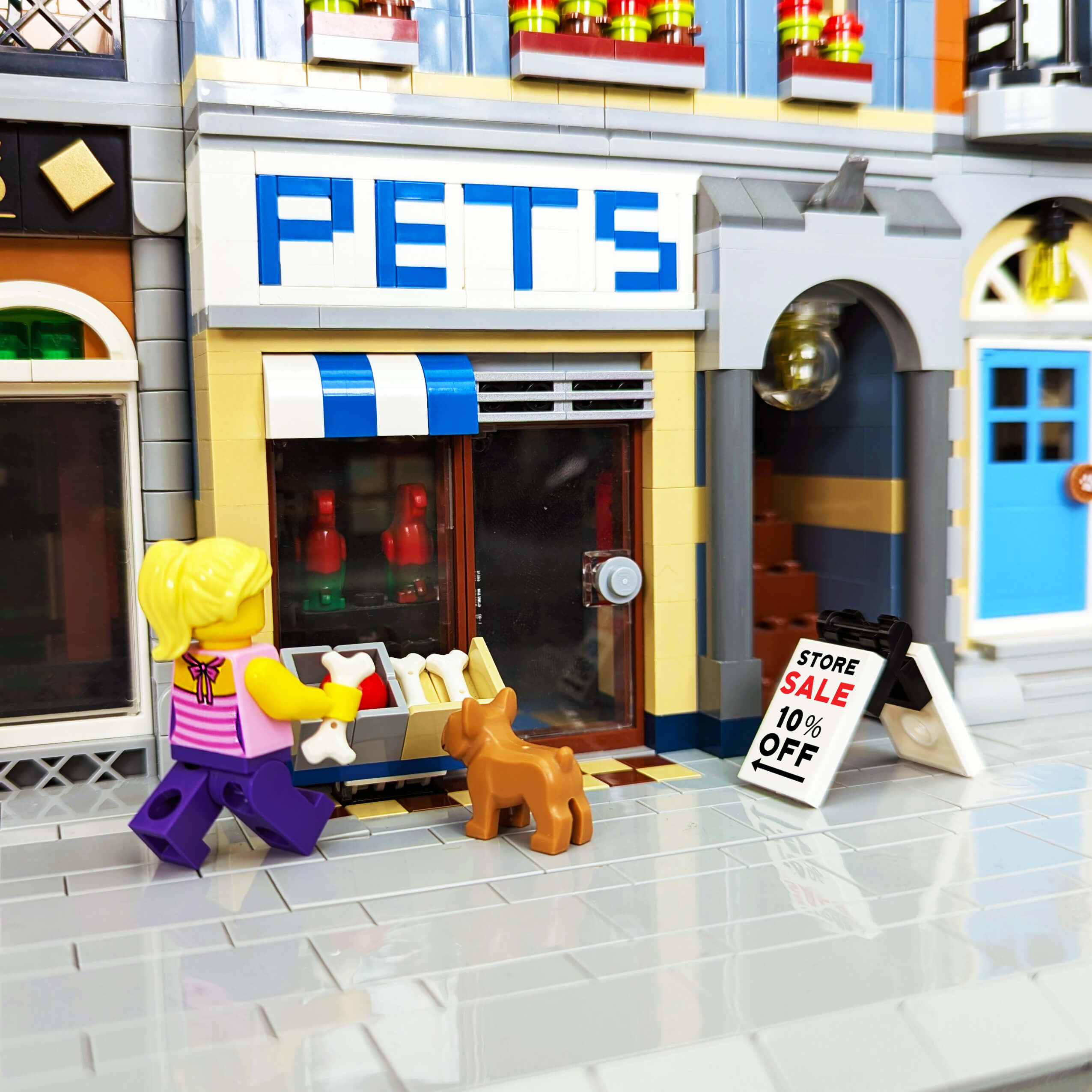 LEGO store with a 'Pets' sign, a LEGO character with a dog, and a sale sign.